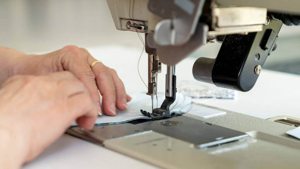 Zu sehen ist eine Nahaufnahme einer Nähmaschine. In dieser Akustik Manufaktur entstehen zum Beispiel Akustikbilder als Kunstwerke in Handarbeit.